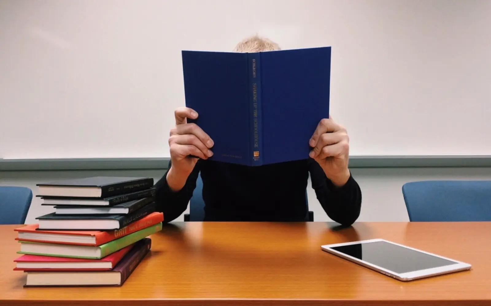 A student reading at a desk with a stack of books